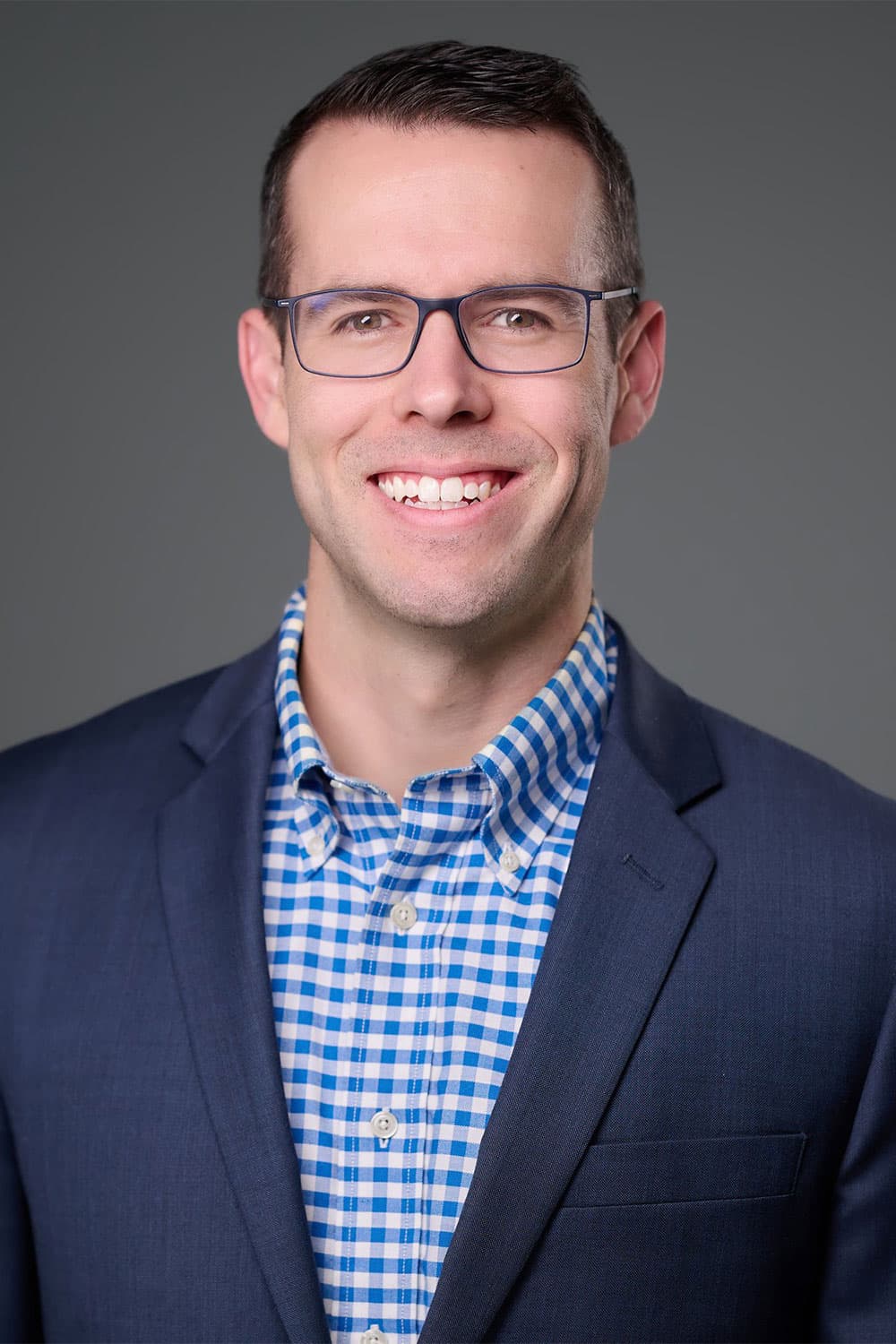 Dr. Stanley Jordan smiling wearing a blue suit jacket and blue and white checkered button down. Eye doctor, ophthalmologist Marietta, eye surgeon, cataract surgeon, glaucoma specialist, ICL implantable lens expert.