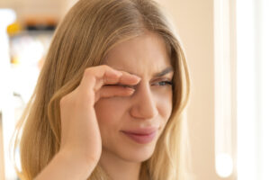 Young woman putting hand over injured eye