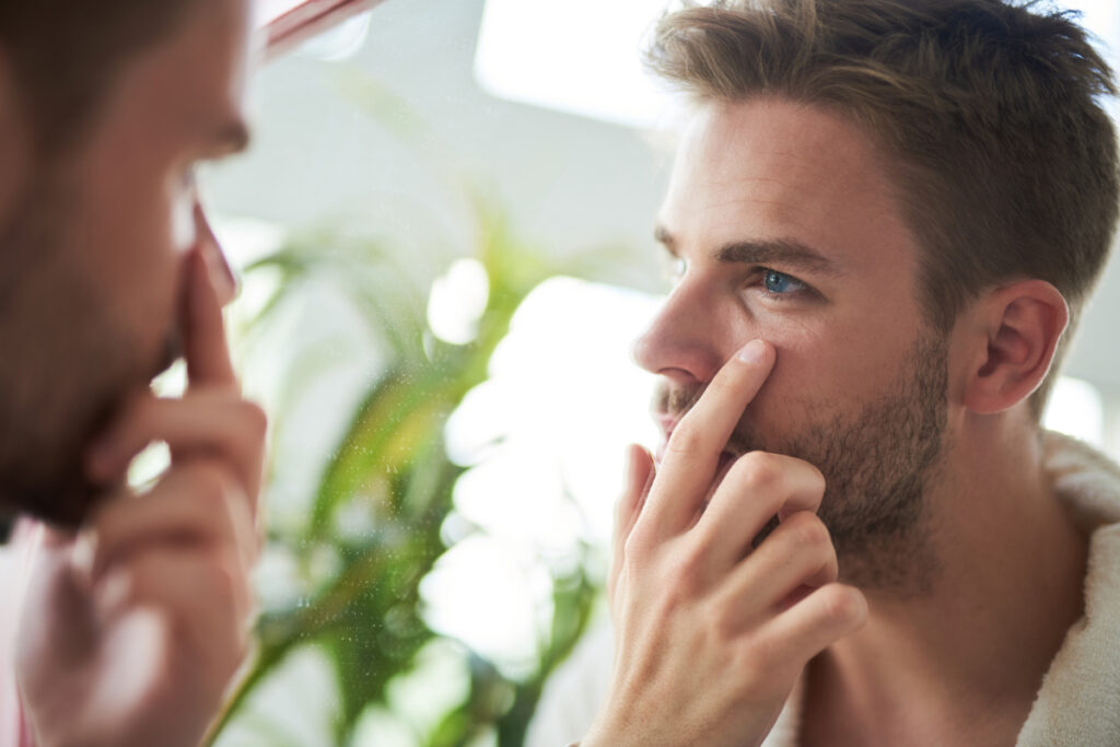 Man touching eyes in mirror